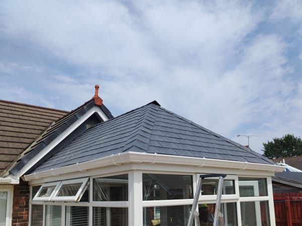 Conservatory roof replacement part-way through, new tiles being laid over the new structure