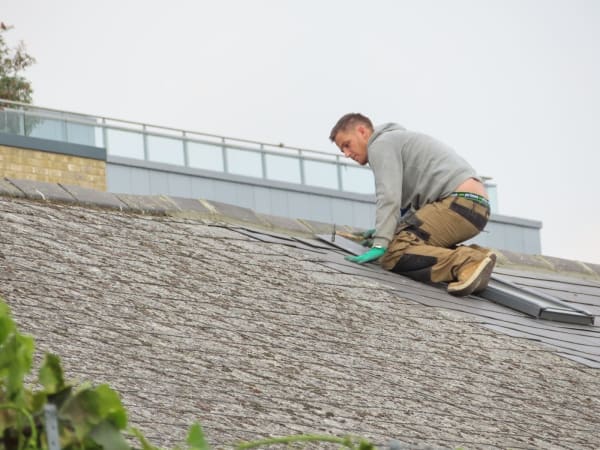 Roofer carrying out an emergency roof repair on a pitched roof in Carlisle