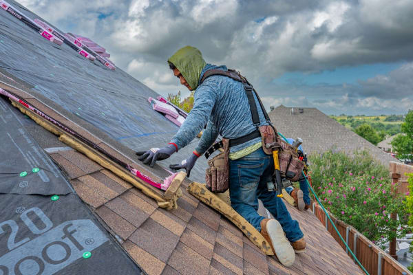 Roofer fixing a new covering over fresh membrane during a Mansfield roof replacement