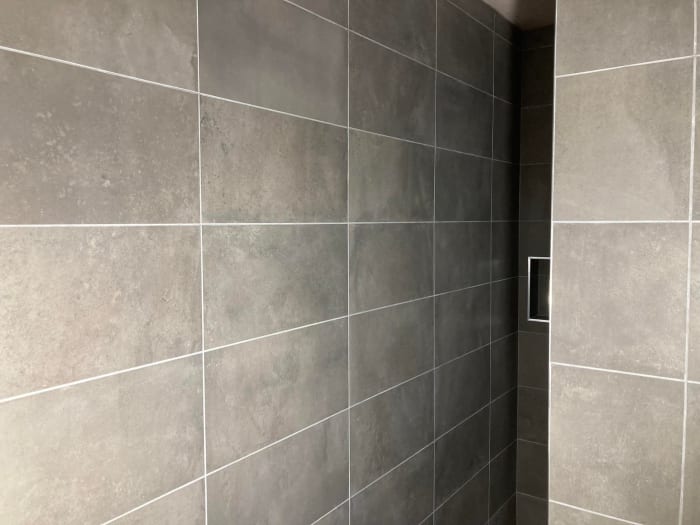 Gray tiled shower with a recessed soap dish.