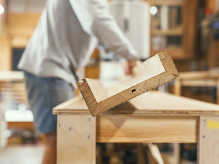A jointed cabinet carcass being lifted onto the bench for dry assembly