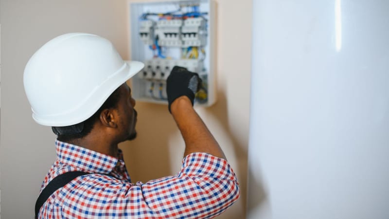 Commercial electrician carrying out electrical maintenance at a Bristol business