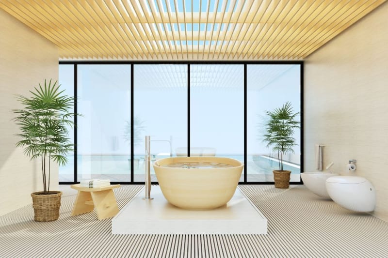 Modern bathroom with a wooden bathtub, large windows, and plants.