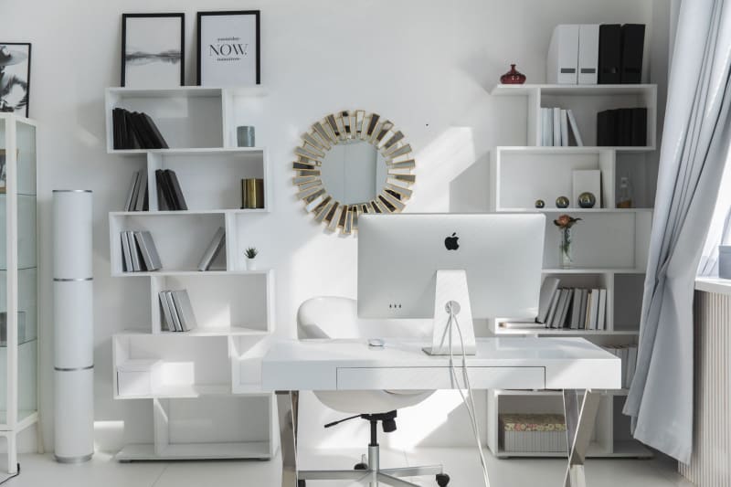 Bright home office with white fitted shelves and desk