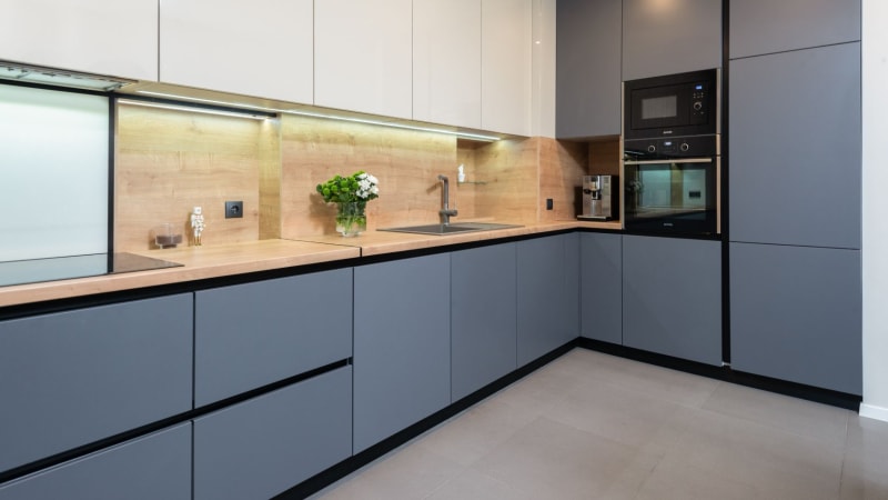 Modern kitchen with gray cabinets, wooden countertops, and built-in appliances.