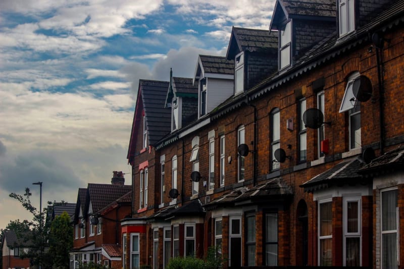 A street of red brick and stone terraced houses with slate roofs and chimney stacks, typical of Carlisle's older housing