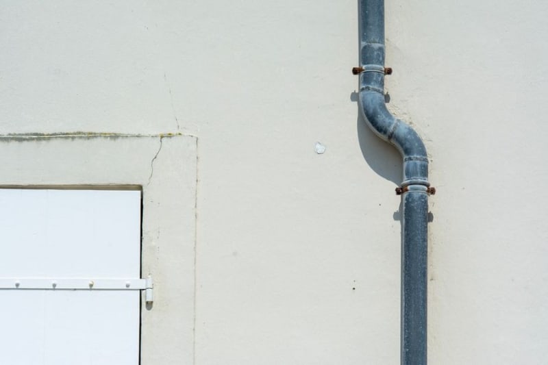 Rainwater downpipe running down an external wall, carrying water from a flat roof outlet