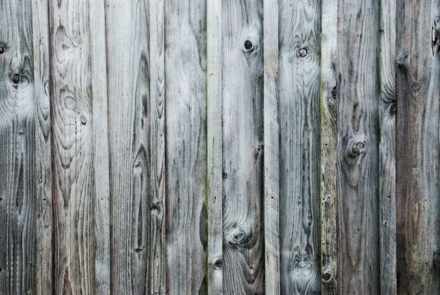 Weathered gray wooden fence with vertical planks and visible knots