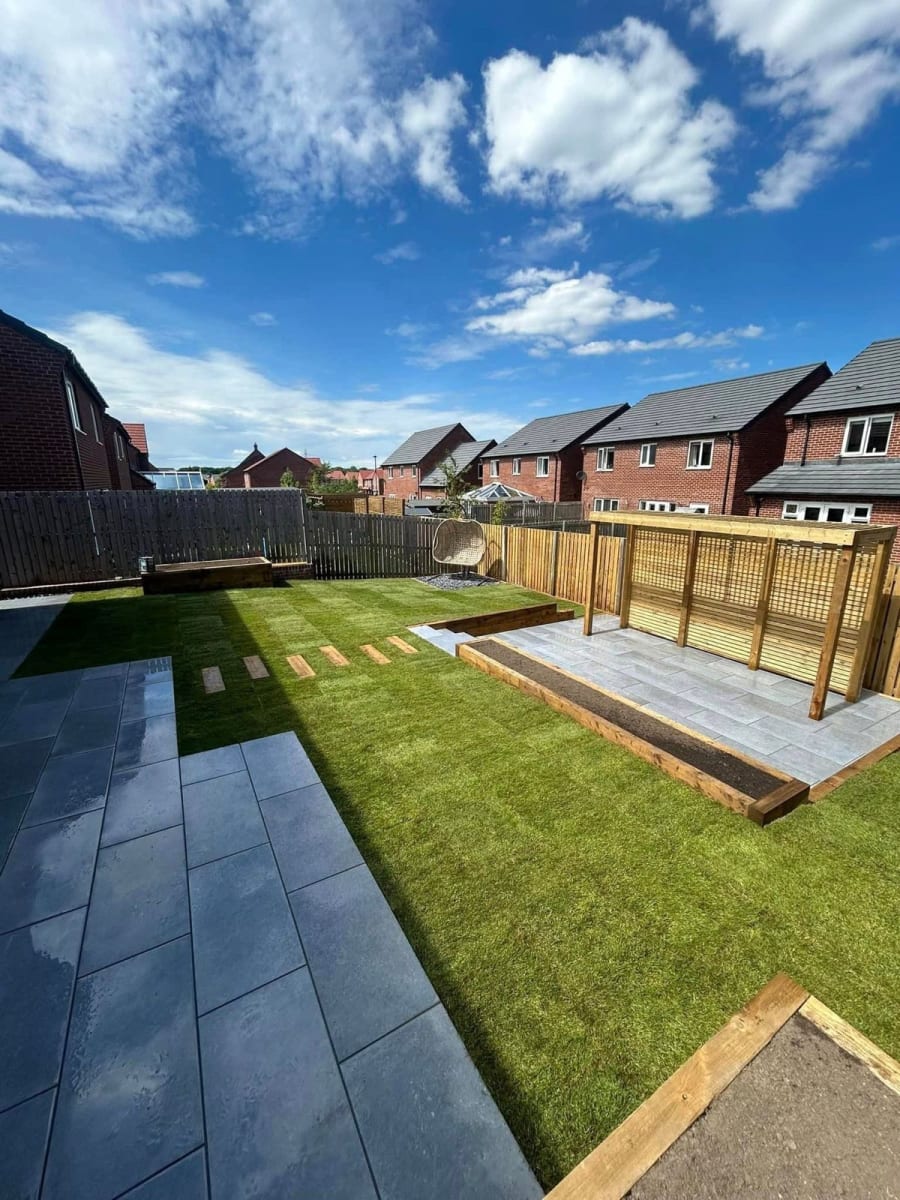 A multi-level backyard with wooden retaining walls, a staircase leading to a grass area, and gravel ground cover.