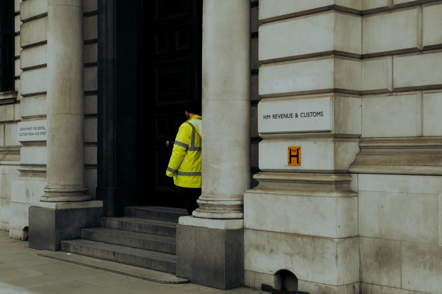 Person in a bright yellow jacket standing in a building doorway beside stone columns