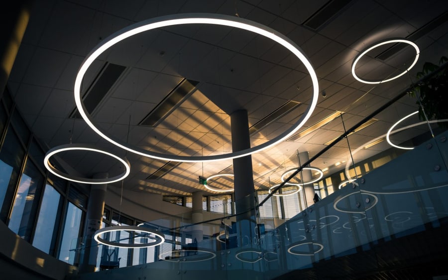 Modern interior with large circular ceiling lights and tall windows in a spacious atrium