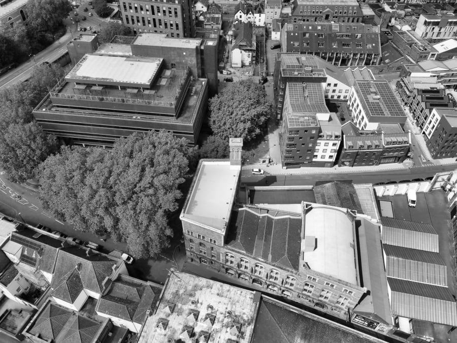 Aerial view of a city block with buildings, trees, and streets in black and white
