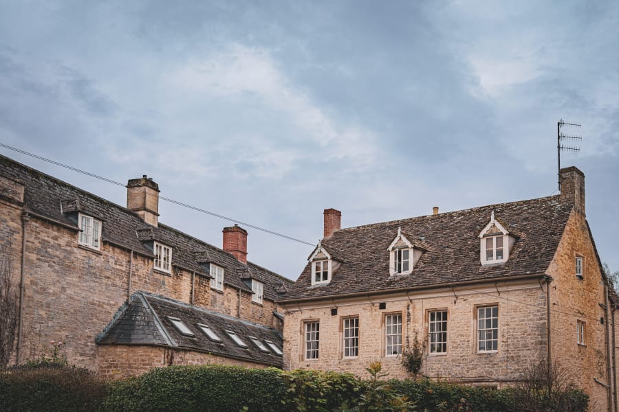 Historic stone buildings with dormer windows under a cloudy sky