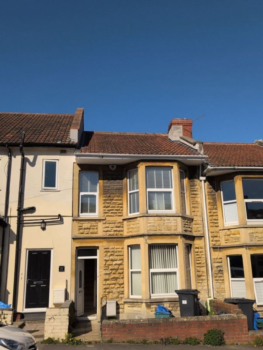 Row of terraced houses with cream brick facades and red-tiled roofs under a clear blue sky