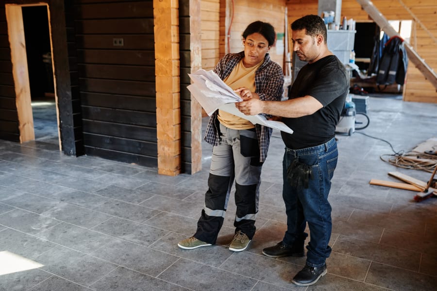 Two people reviewing plans in an unfinished building interior