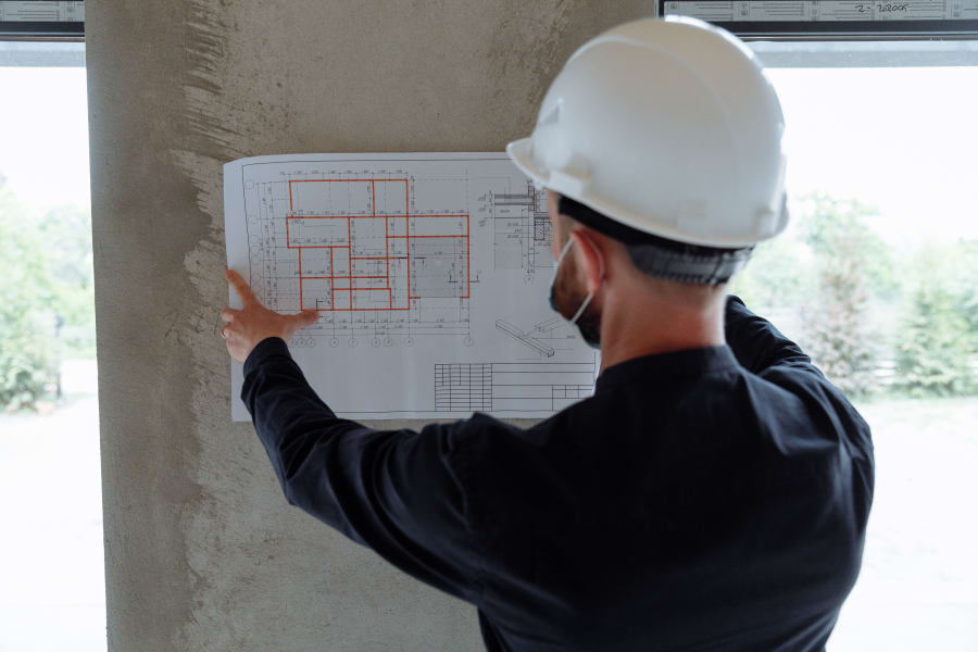 Construction worker in a hard hat reviewing blueprints on a wall at a building site