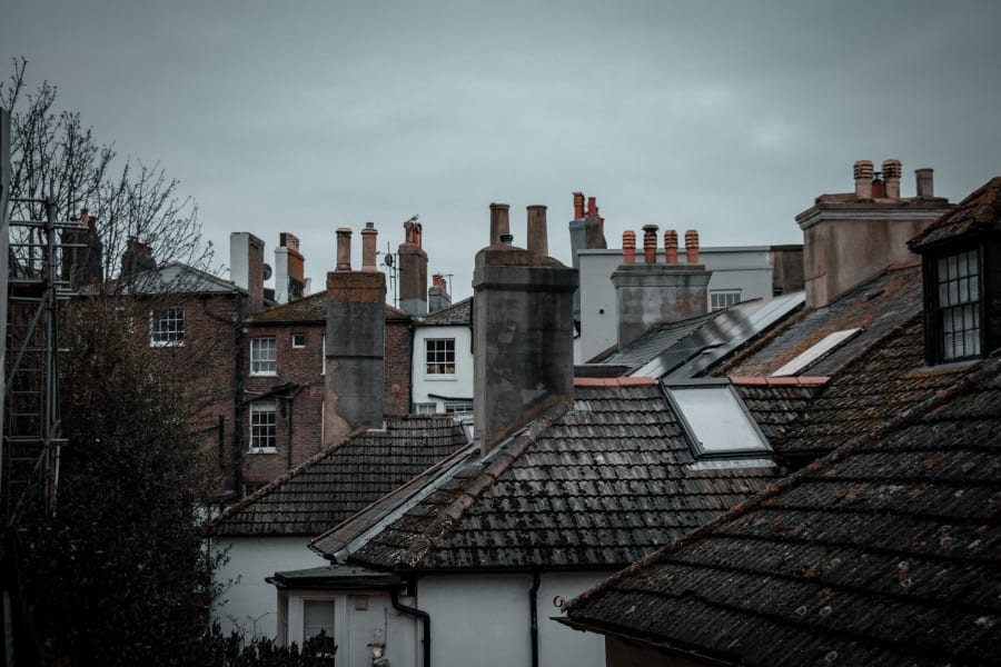 Rooftops and chimneys of old brick houses under an overcast sky