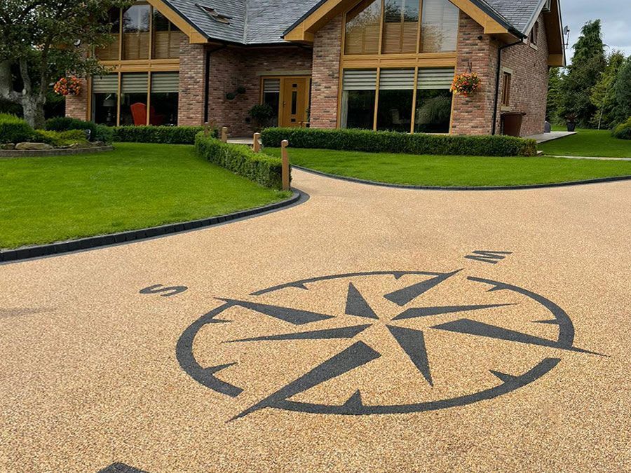 Brown resin driveway with a black compass pattern, outside a large building