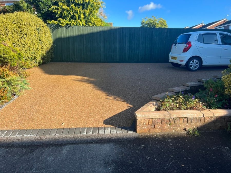 Grey resin driveway with a red van parked on it, with grey block paving border surrounding