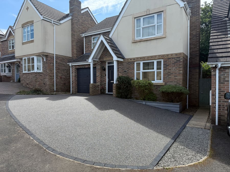 After photo of grey resin driveway in front of red brick house.