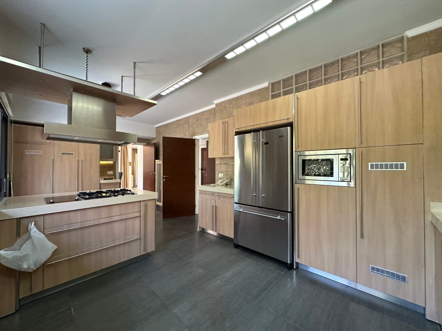 Modern kitchen with wood cabinets, stainless steel appliances, and dark flooring in a bright open space