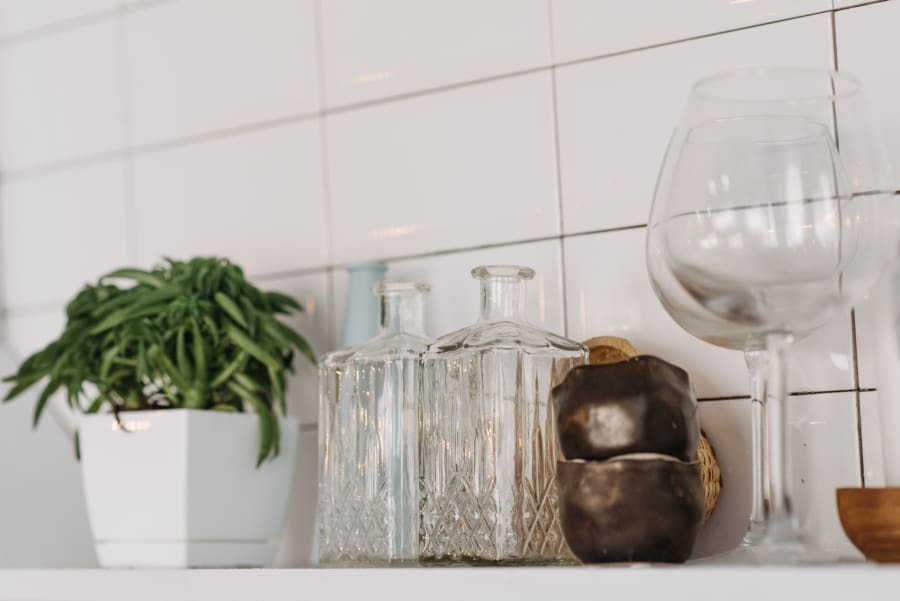 Potted plant, glassware, and wine glasses on a tiled kitchen shelf