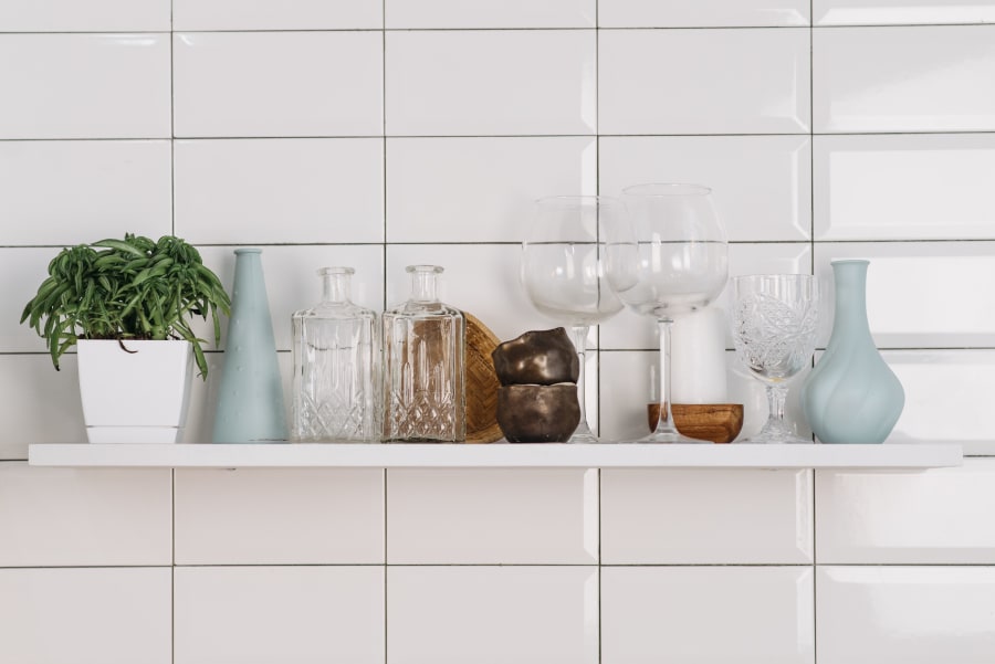 White tiled shelf with potted plant and assorted glass jars and vases