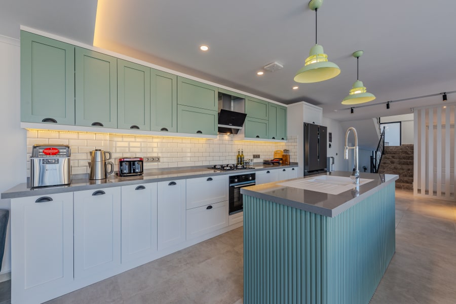 Bright modern kitchen with mint cabinets, white counters, pendant lights, and a central island