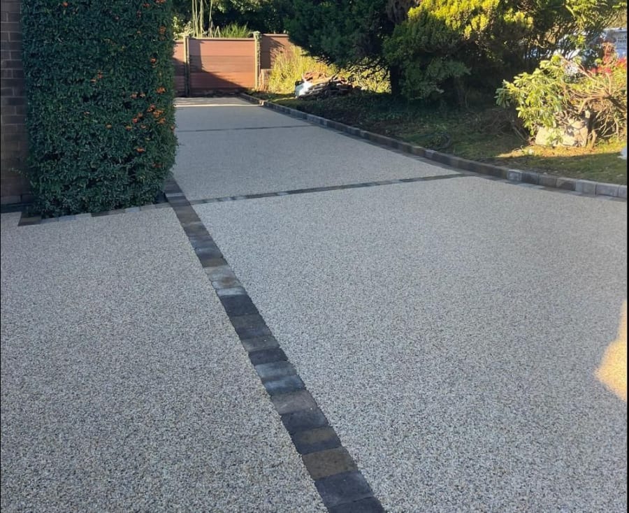 A grey resin driveway and patio with a black and dark grey compass shape at the entrance.