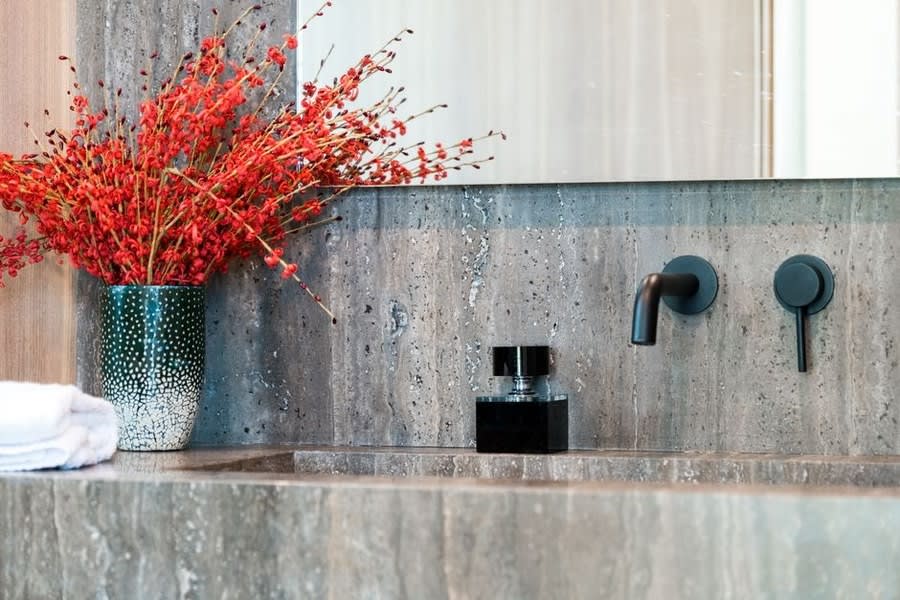Wall-mounted black mixer taps set into a blue-green stone surround