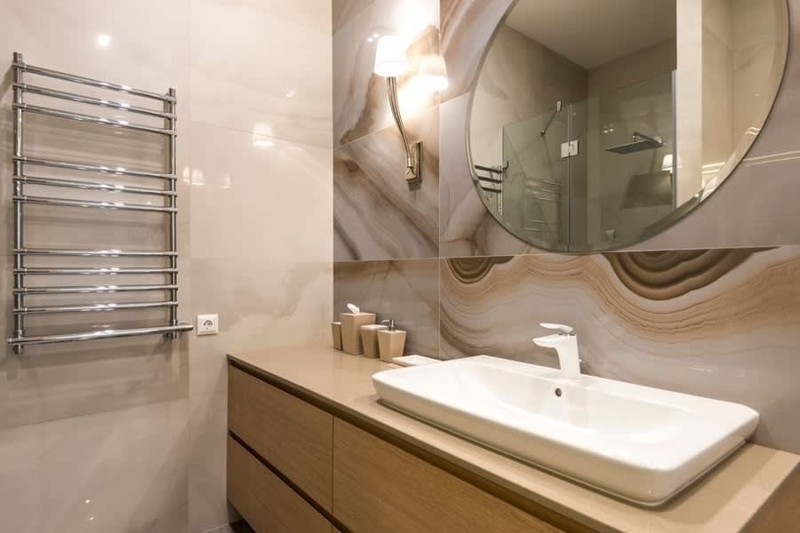 Onyx-effect wall panel above an oak vanity unit with a rectangular basin