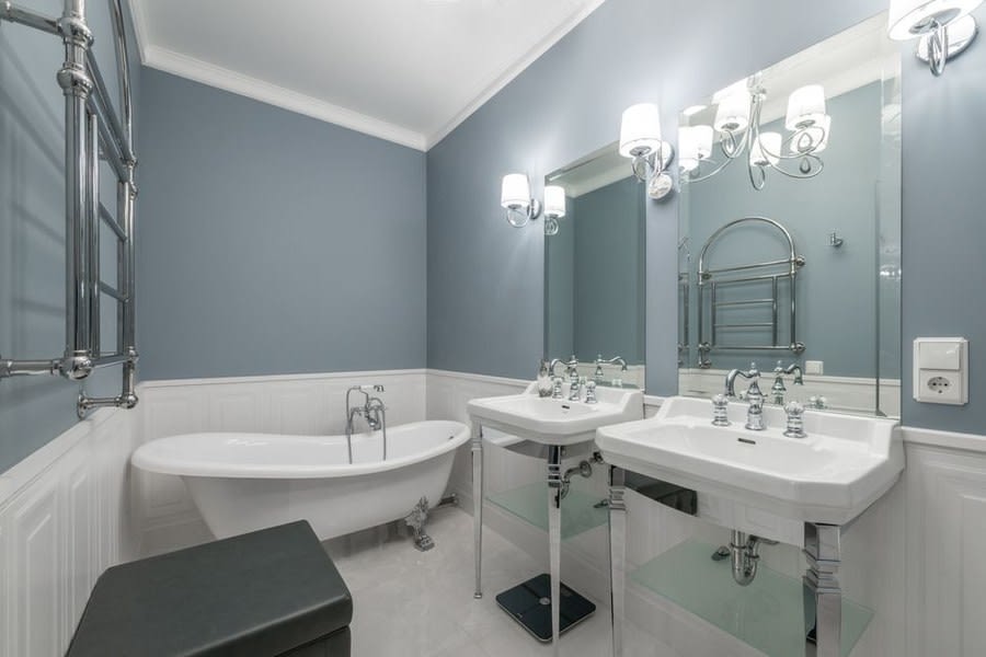 Period bathroom design with a roll-top bath and twin pedestal basins in a soft blue-grey scheme