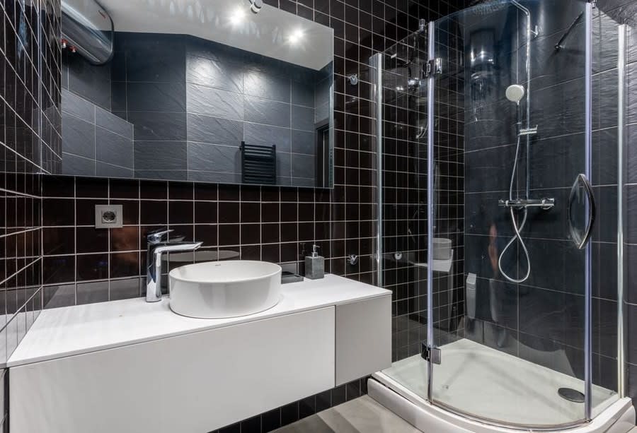 Dark tiled bathroom with a white floating vanity and quadrant shower enclosure