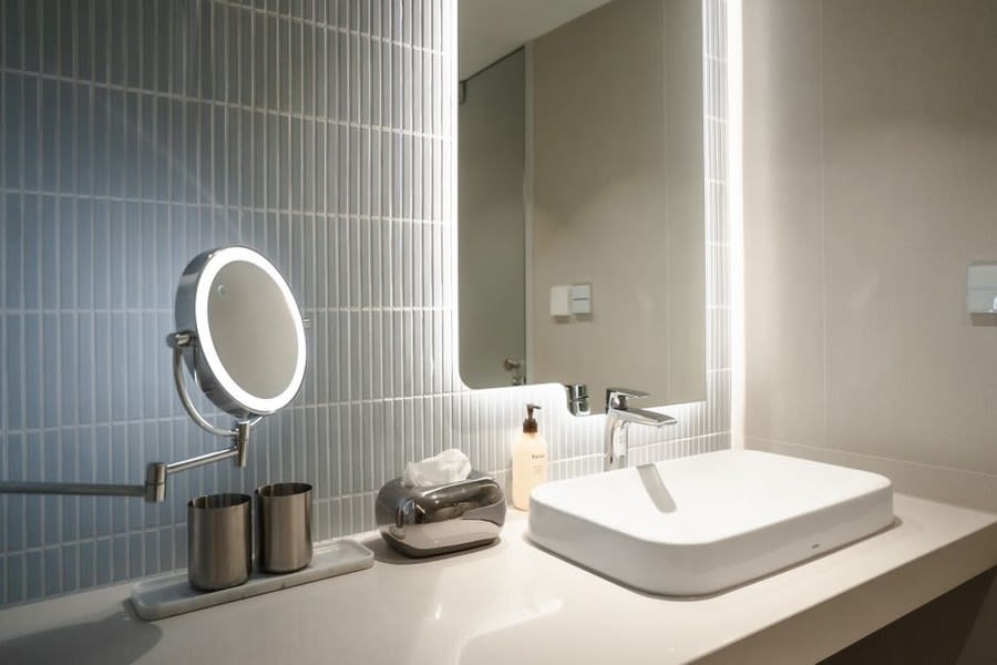 Fluted vertical wall tiling behind a wide rectangular basin and backlit mirror