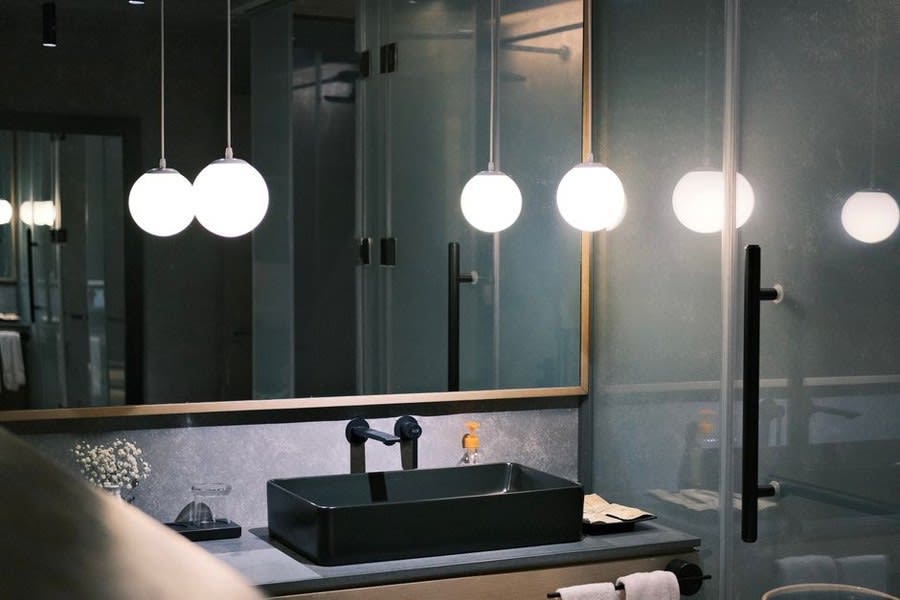 Brass tap detail on a dark stone vanity with pendant lighting above