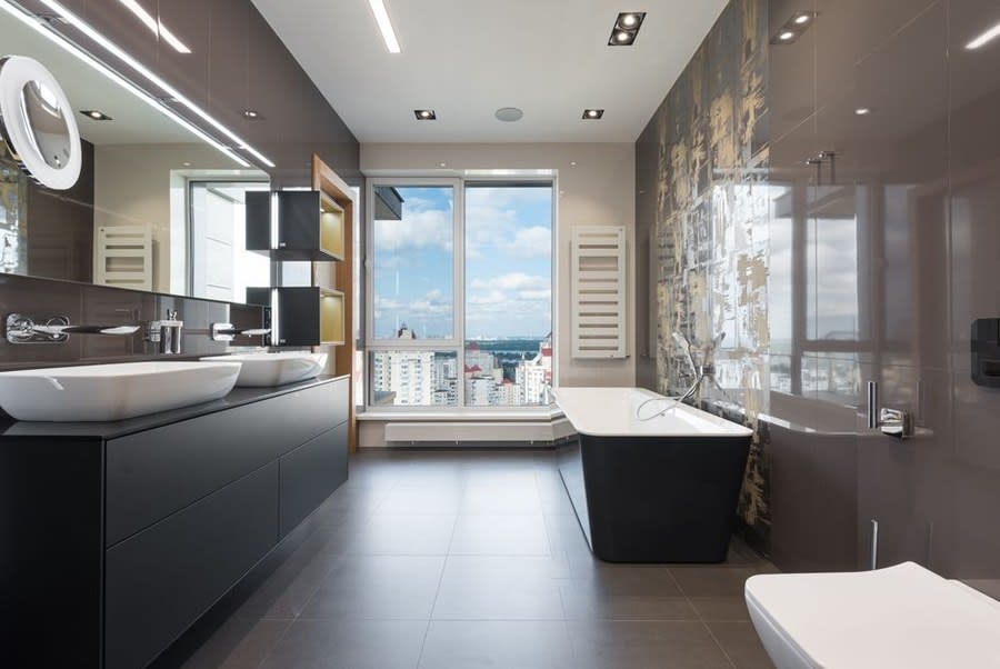 Marble bathroom with a freestanding bath positioned beside floor-to-ceiling glazing