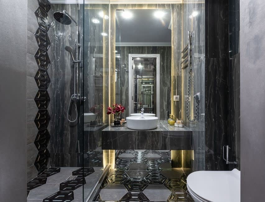 Dark marble bathroom with brass fittings and a mirrored recess