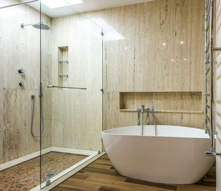 Wet room installation in Exeter with travertine walls, a freestanding bath and level-access shower