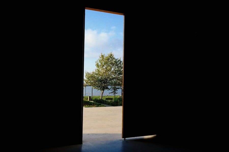 View through open glass door threshold to garden and sky beyond