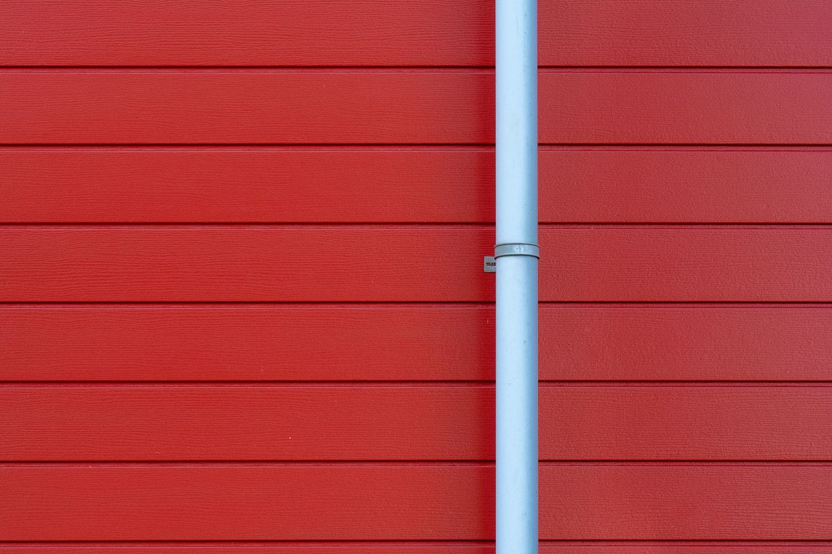 Red wooden wall with a vertical white pipe in the center