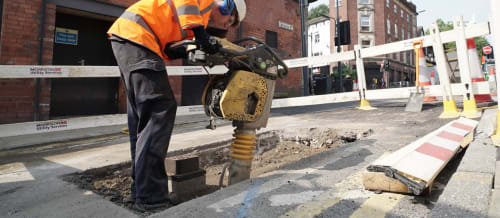 Heffernan utilities worker wearing a hard hat and earmuffs whilst operating heavy machinery