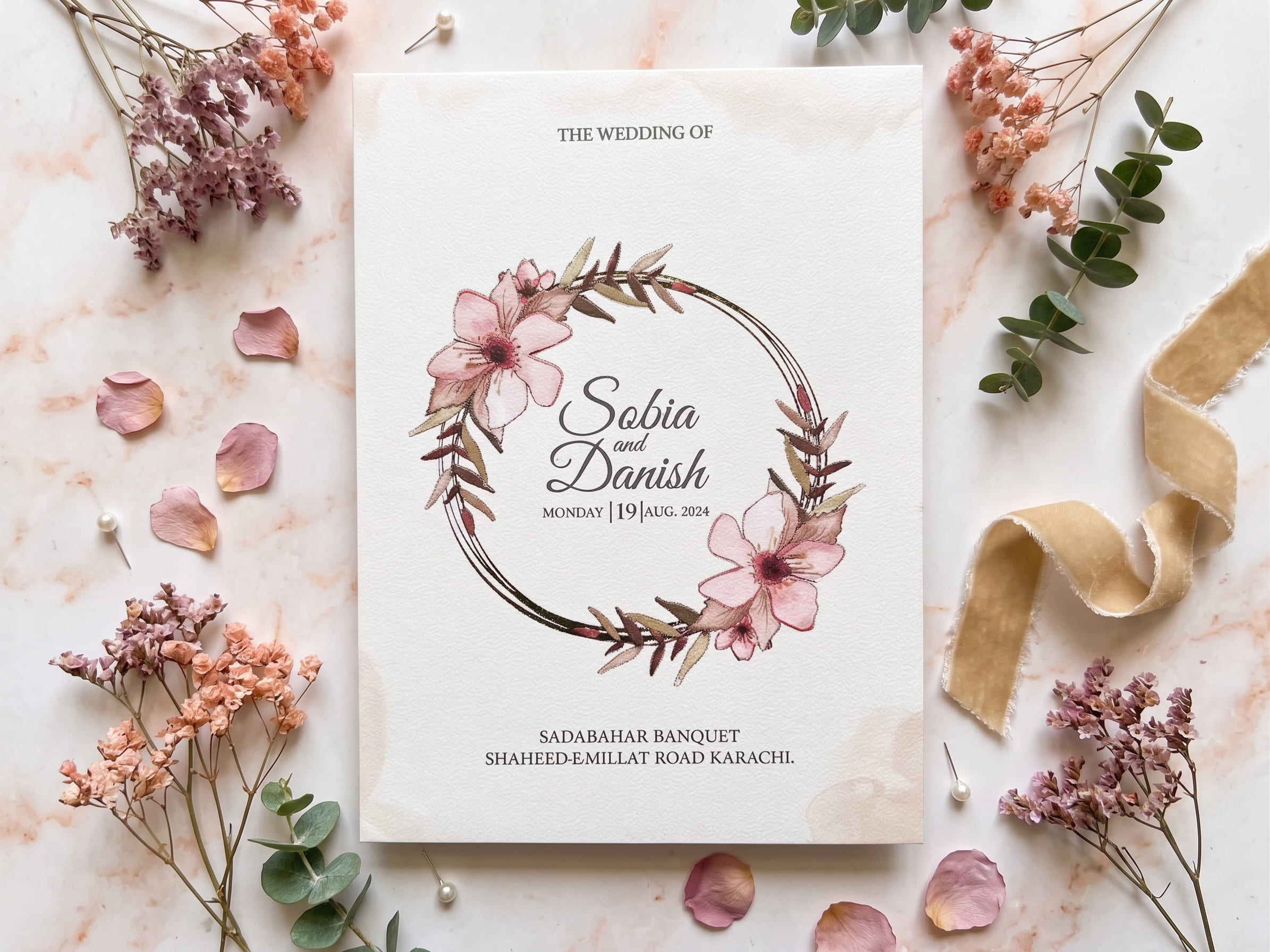Cream wedding invitation card with thin gold geometric lines and pink watercolour florals in the corners by Shahi Bulawa Karachi
