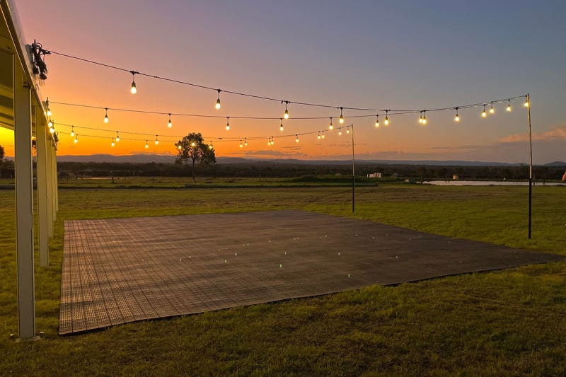 Festoon lighting hire Brisbane — warm white festoon lights under a clearspan marquee at sunset
