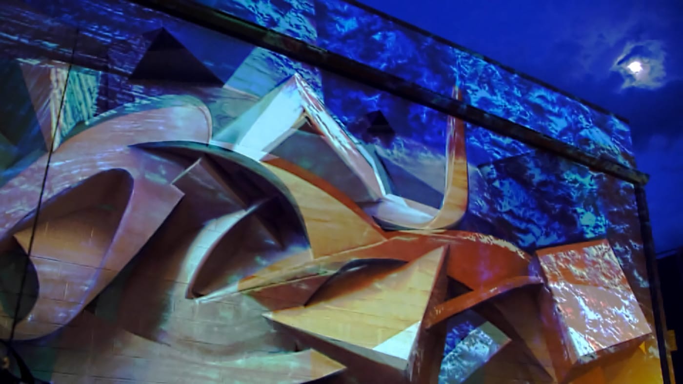 Wide shot of Illuminous FOCO projection mapping installation on historic building Fort Collins Colorado night