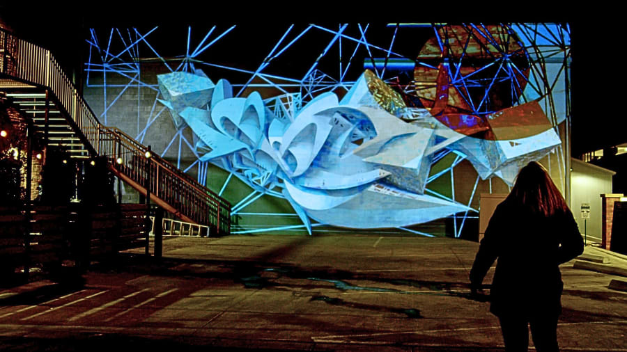 Detail of Peeta mural with projection mapping overlay showing 3D geometric letterforms lit by digital animation Alt Ethos