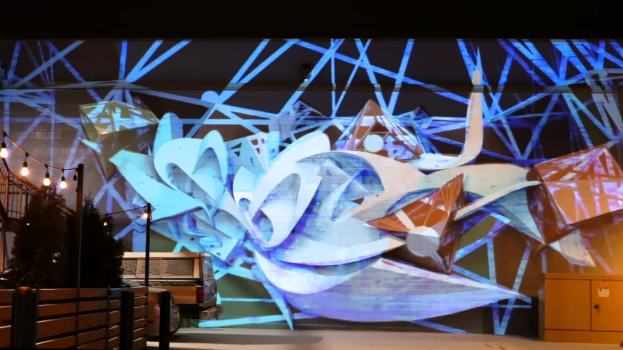 Person silhouetted against Illuminous FOCO projection mapping installation Fort Collins Colorado showing human scale