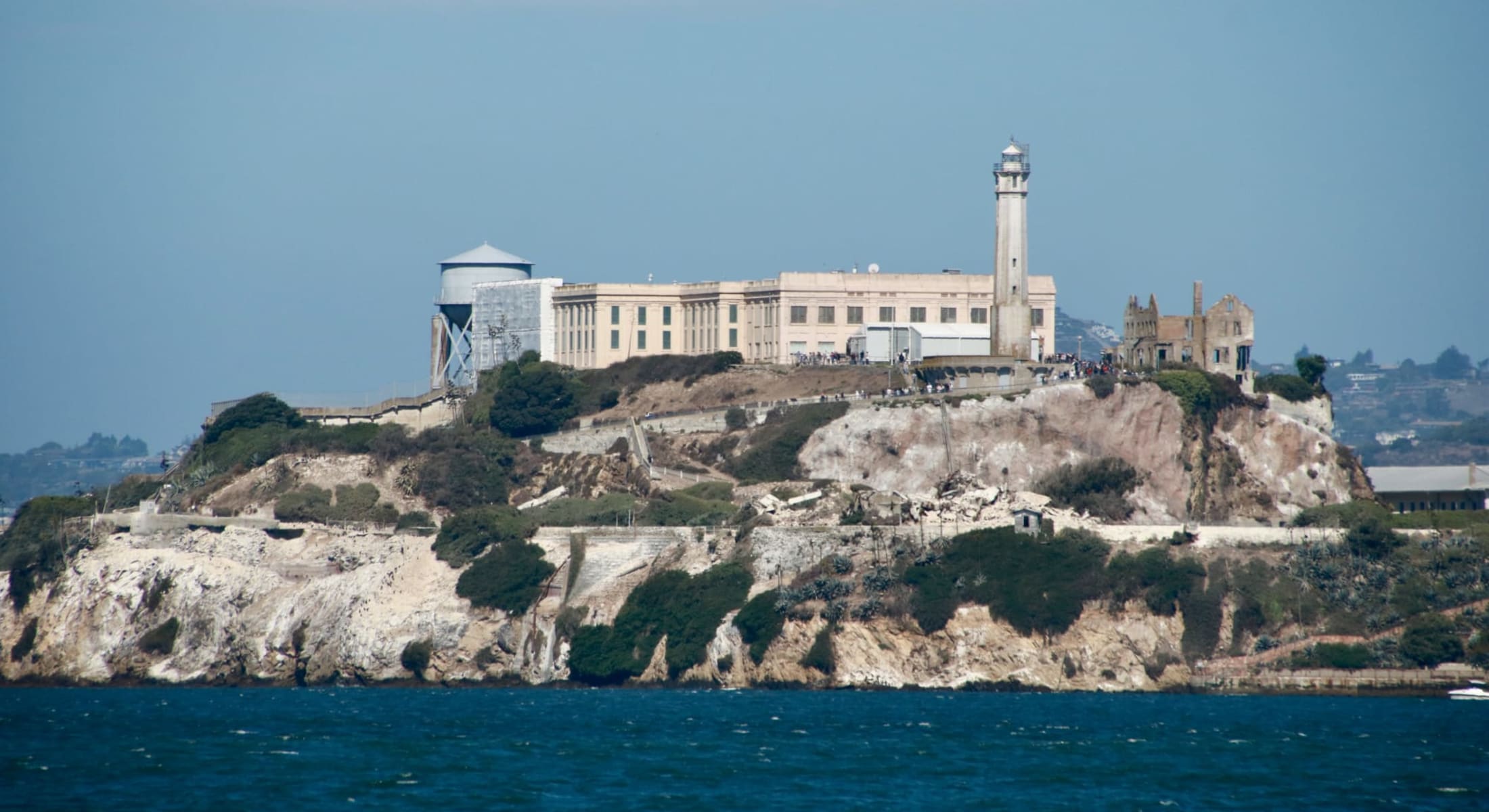Rocky island with institutional building, lighthouse, and water tower in San Francisco bay
