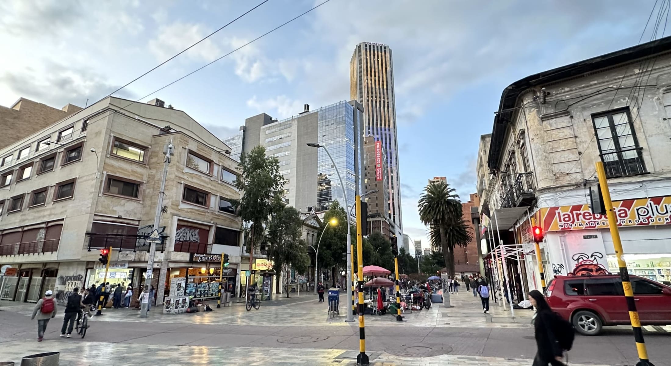 Urban street intersection with palm trees, market stalls, and glass tower in Zona T & Chapinero