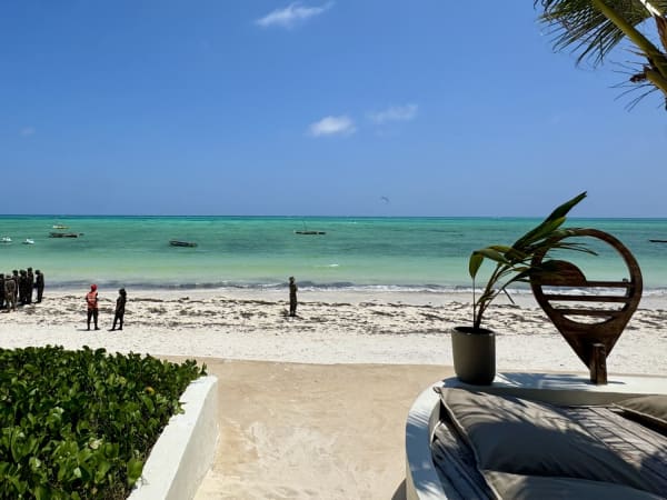 Zanzibar beach shoreline with uniformed group, wooden boats, and terrace lounge area