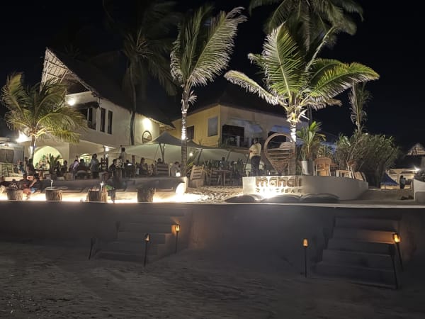 Open-air beachfront bar with thatched roof and low lighting in Zanzibar at night